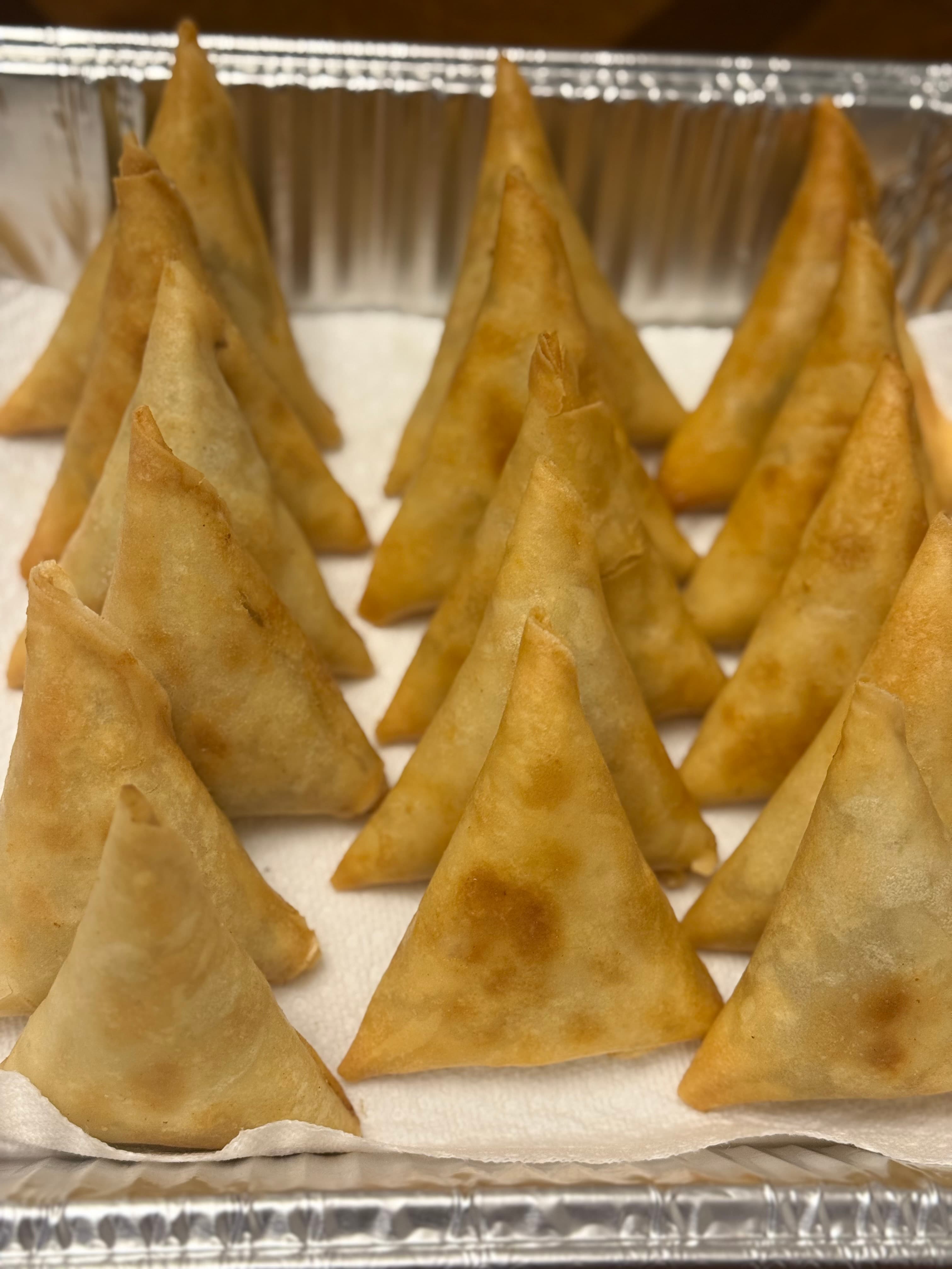 Golden samosas arranged for a gathering